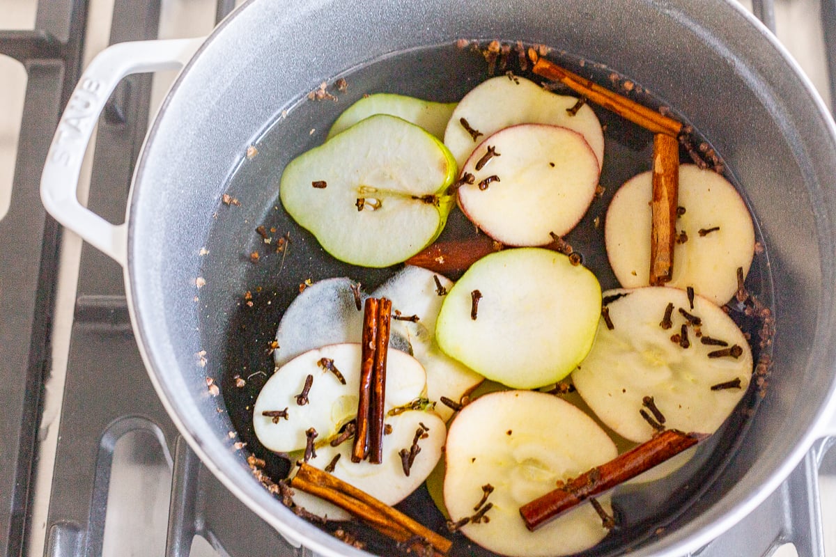 A cast iron simmer pot filled with stovetop potpourri of sliced apples, cinnamon sticks and more!