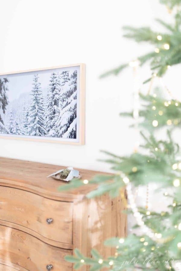 Christmas bedroom decor with a pretty tree, soft wood dresser and art tv.