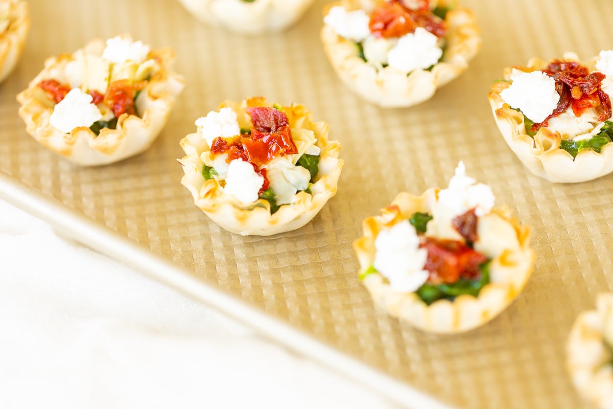 A tray of spinach dip cups, a phyllo cup appetizer filled with delicious spinach dip bites, served on a baking sheet.