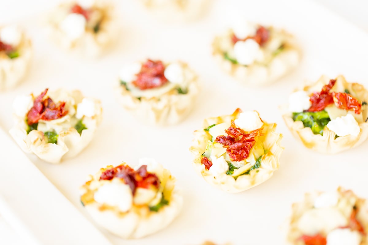 A white plate with small spinach dip cups.