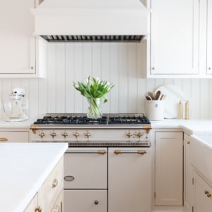 A cream kitchen with unlacquered brass hardware on the cabinets.