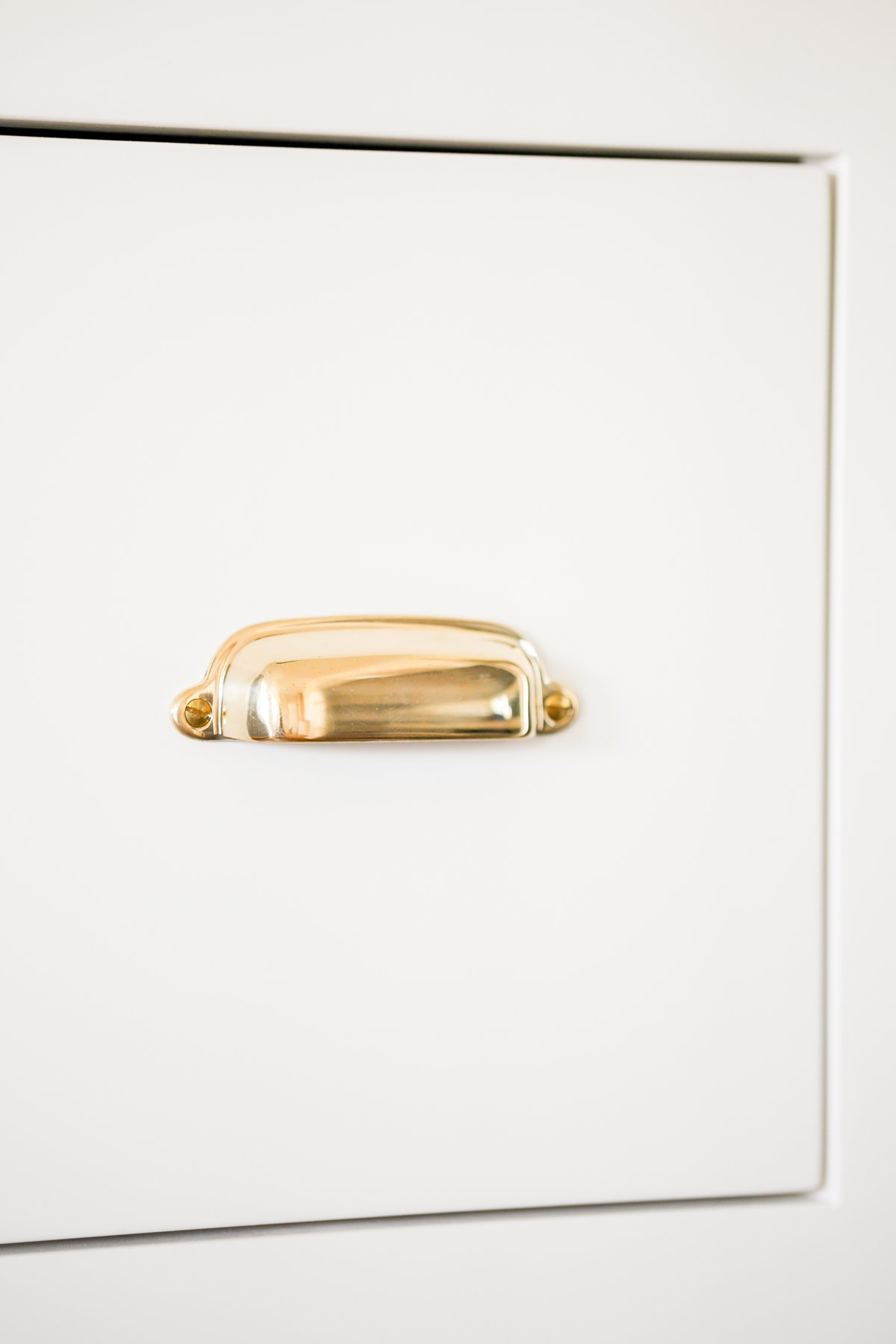 Cream kitchen cabinets with unlacquered brass hardware.