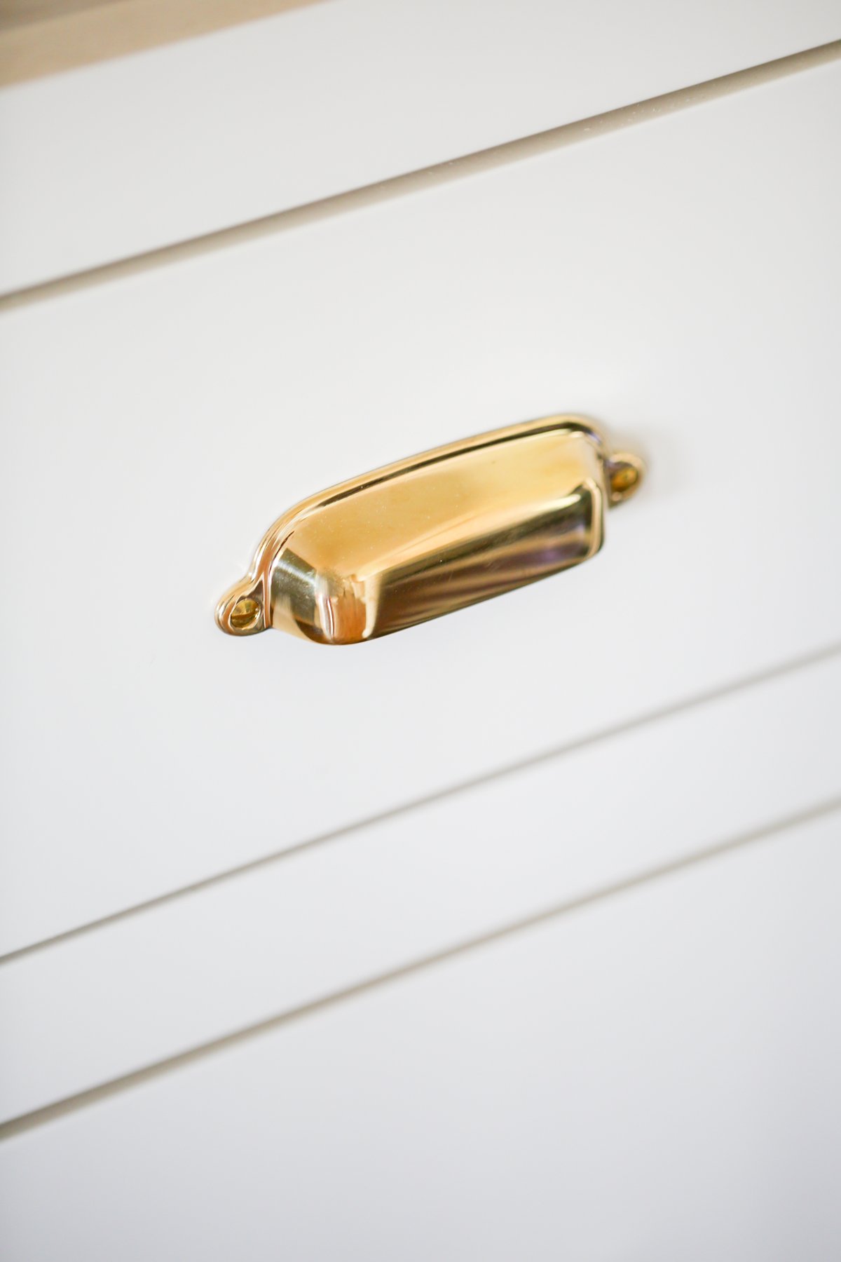 Cream kitchen cabinets with unlacquered brass hardware.