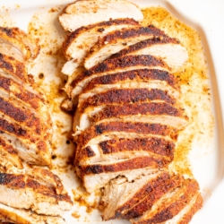 Sliced blackened chicken on a white serving platter.