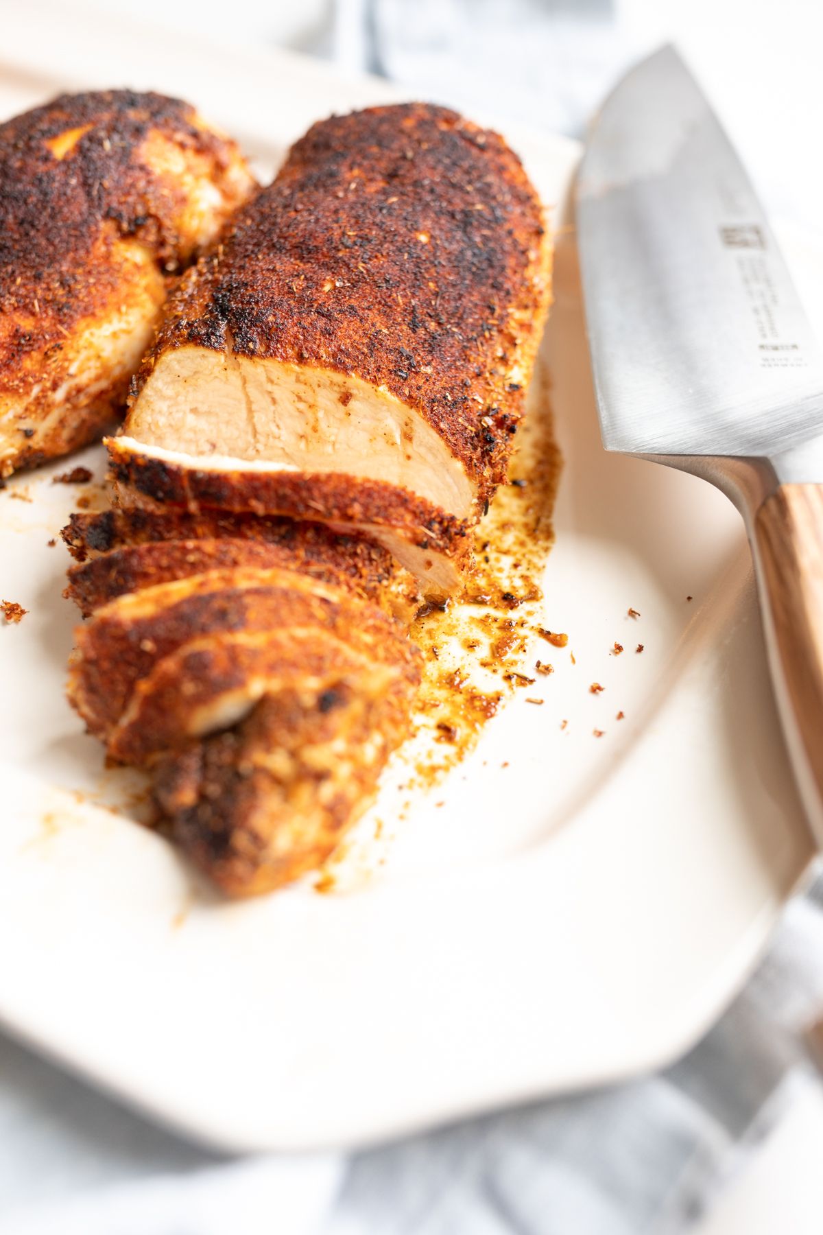 Sliced blackened chicken on a white serving platter.