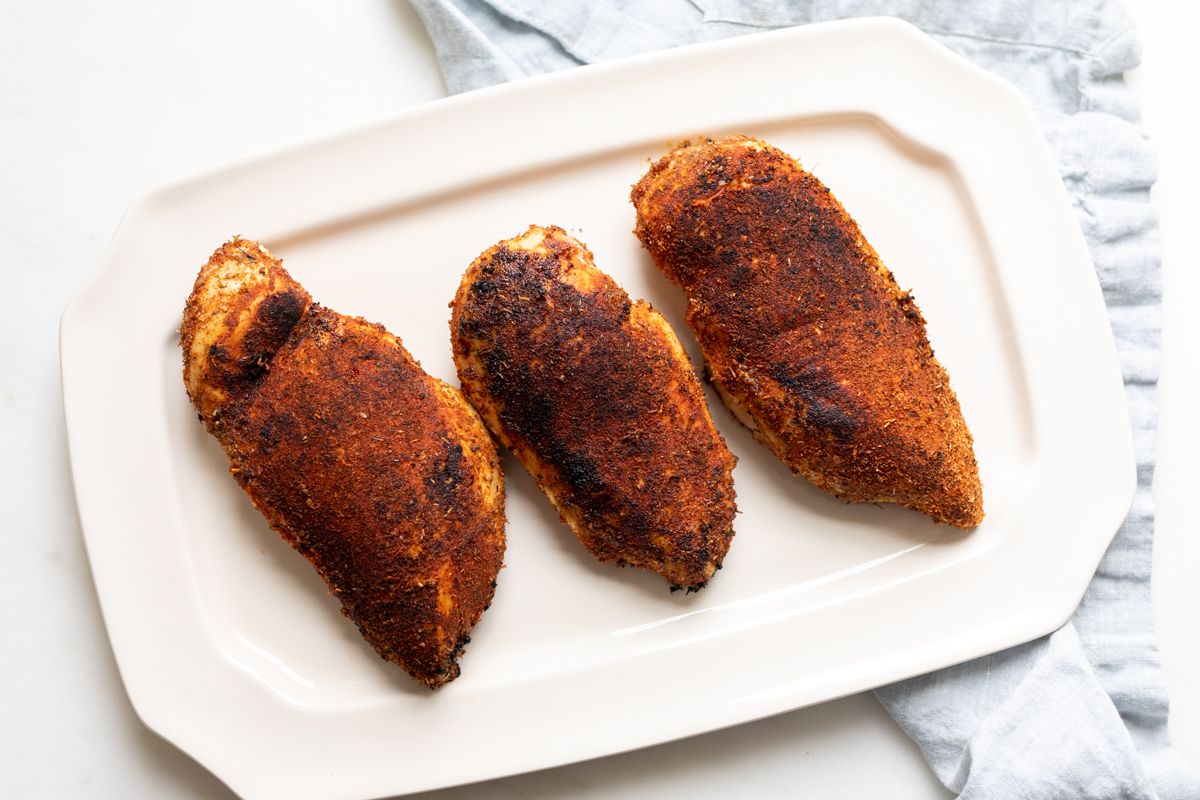 Blackened chicken breasts on a white platter.