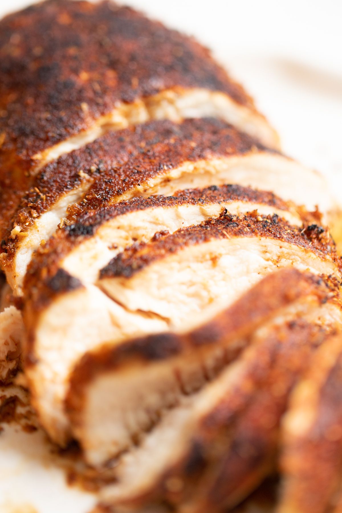 Sliced blackened chicken on a white serving platter.