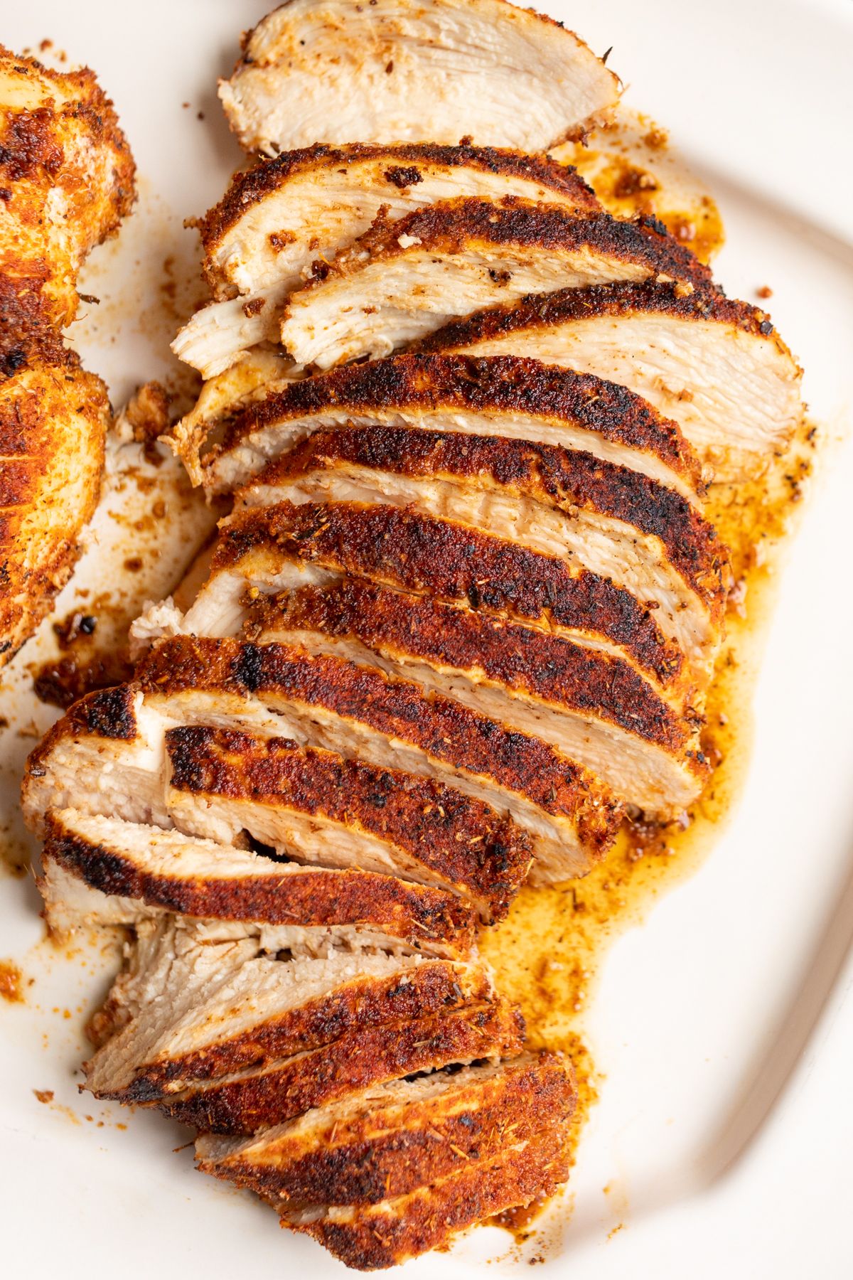 Sliced blackened chicken tenders on a white serving platter.