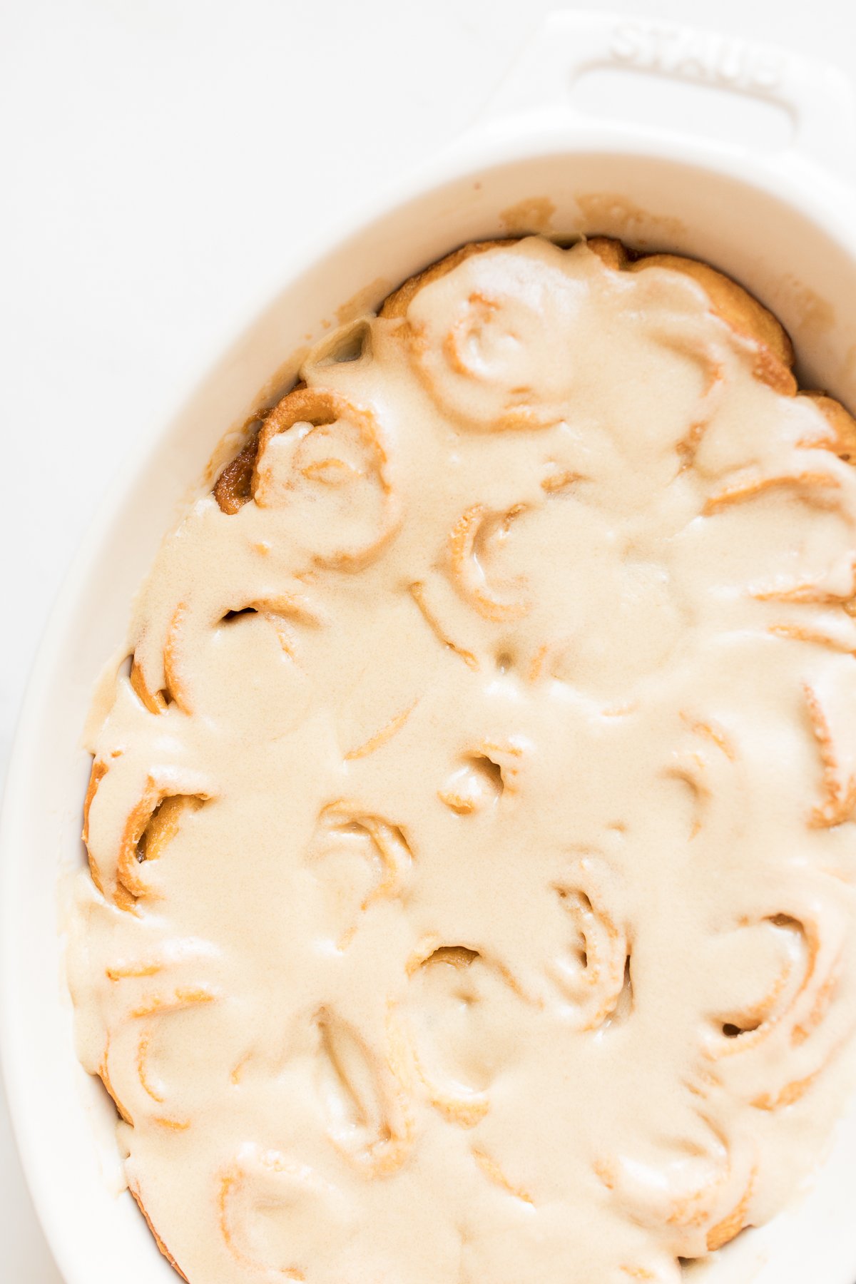 A white dish with caramel rolls.
