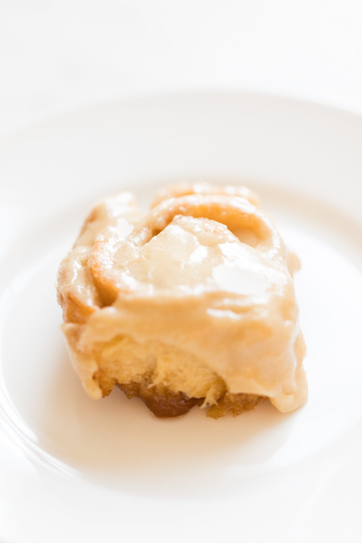 A caramel roll is sitting on a white plate.