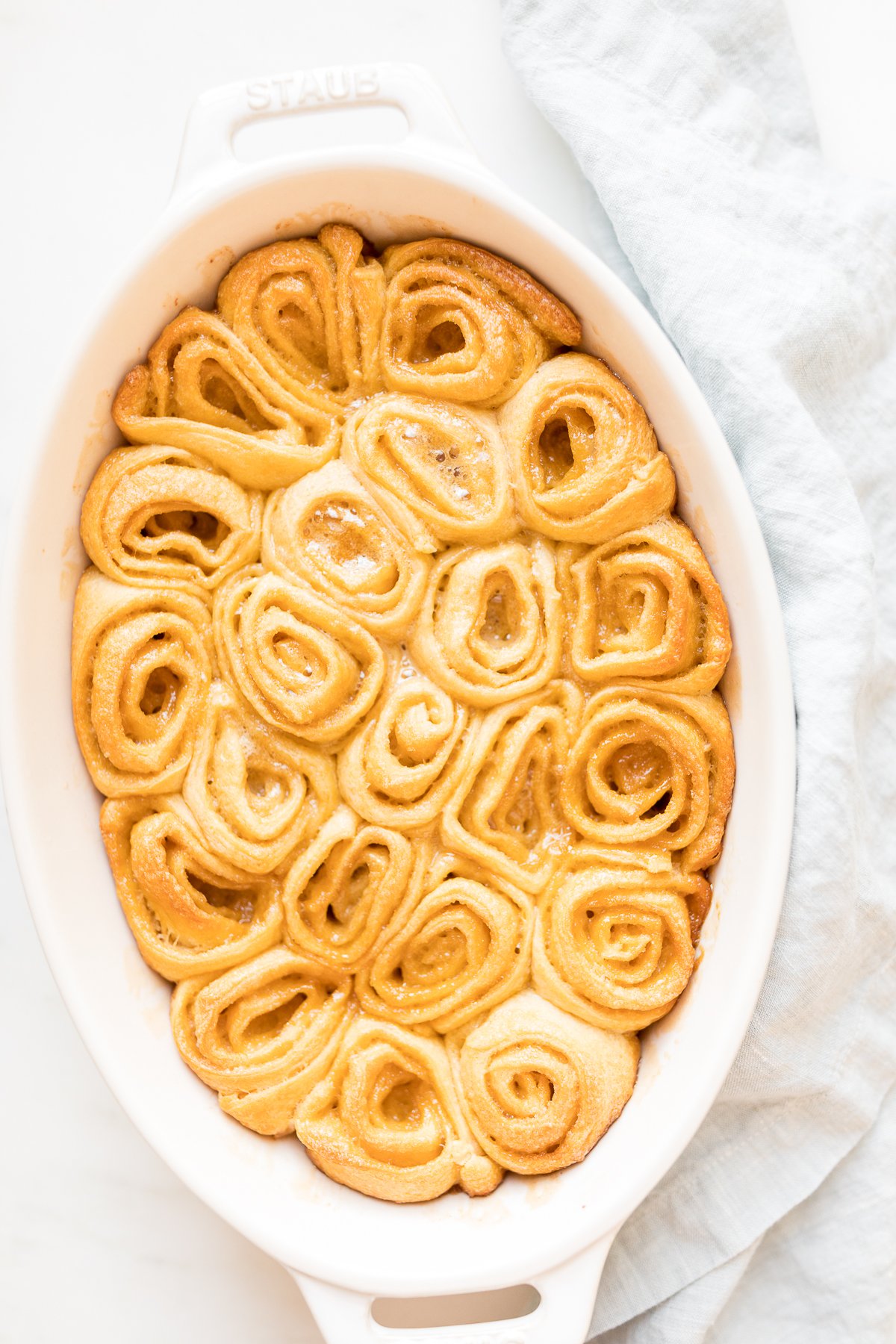 A white dish with a caramel roll in it.