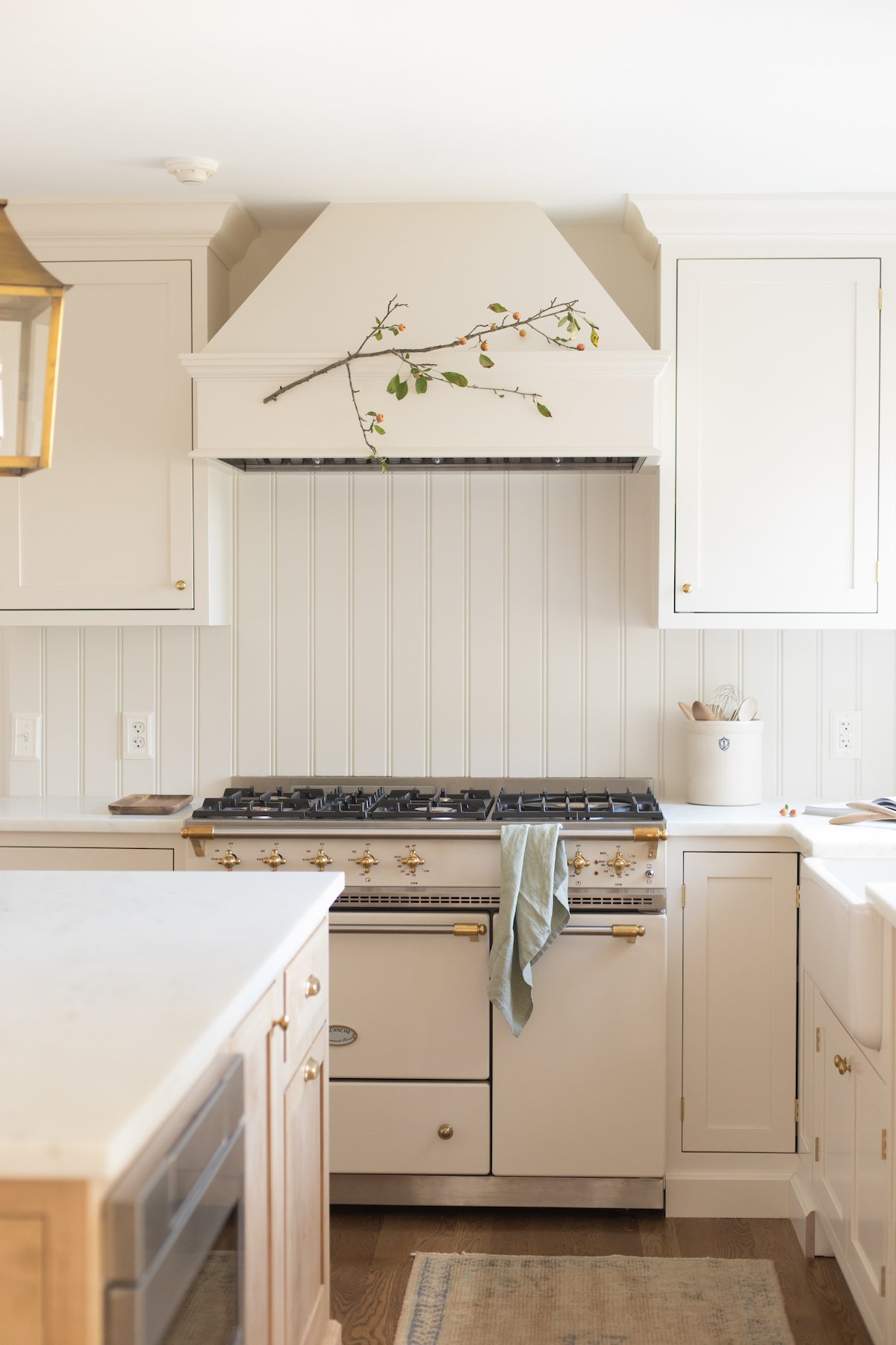 Looking into a kitchen with cream cabinets and a wood island, built in microwave.