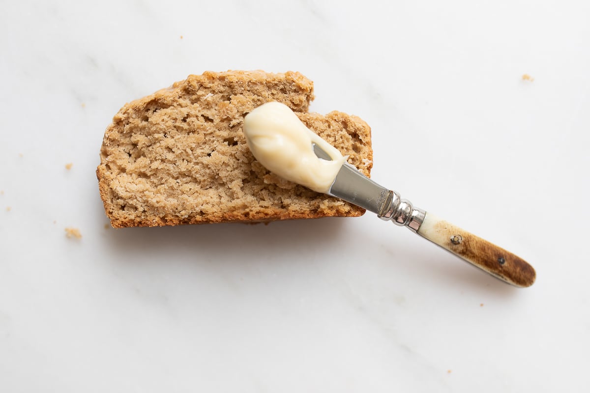 A slice of bread with a knife full of honey butter resting on top