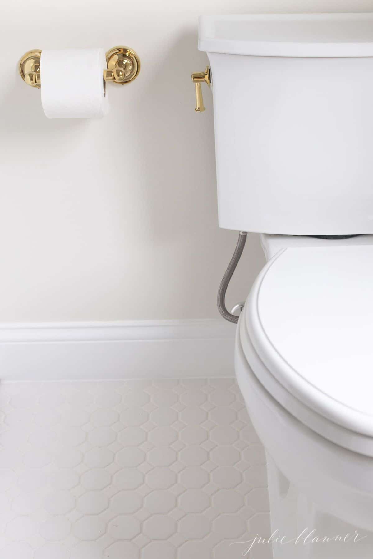 A white tile floor near a toilet in bathroom.