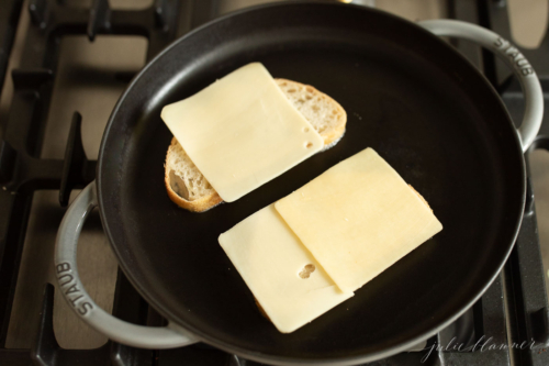 Bread with cheese slices on a stovetop pan for a gourmet grilled cheese.