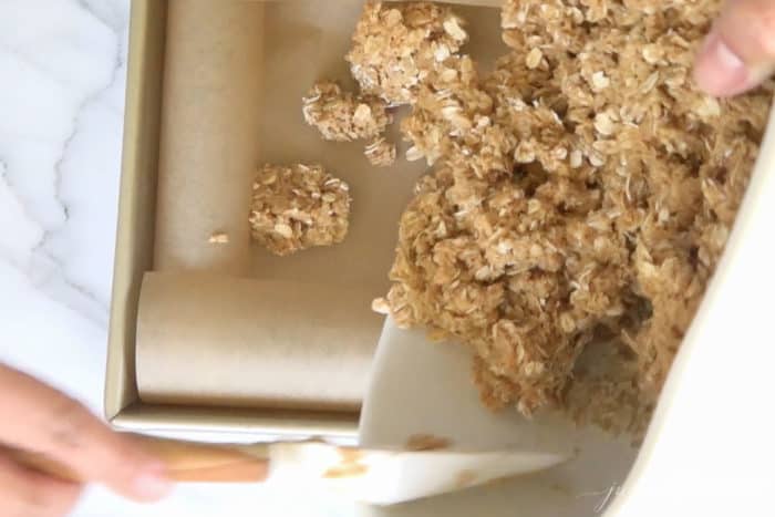 scooping no bake peanut butter bar mixture into baking dish