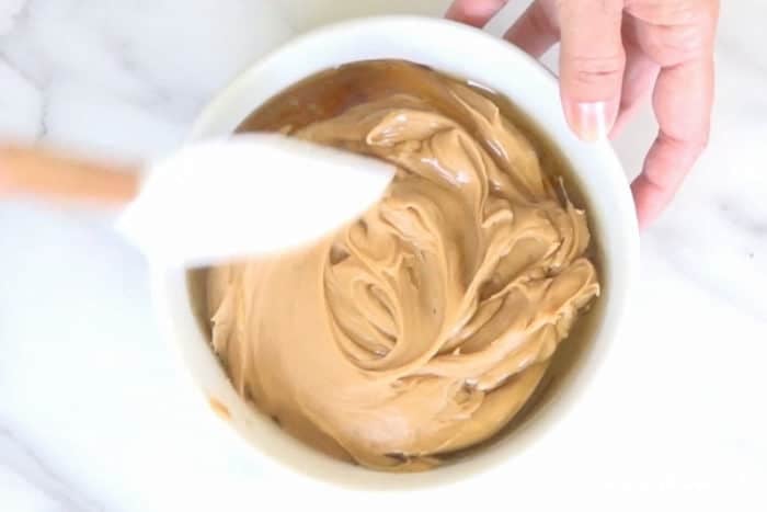 mixing peanut butter and honey together in a white mixing bowl