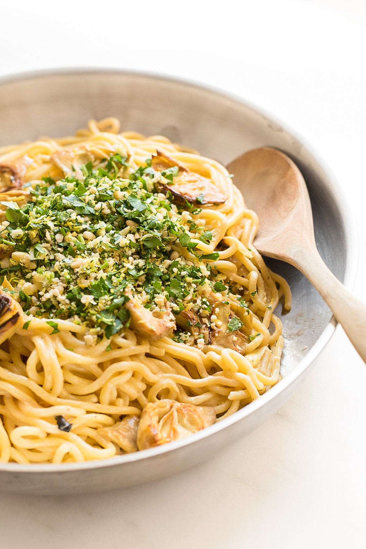 A pan full of lemon spaghetti with fried artichokes.