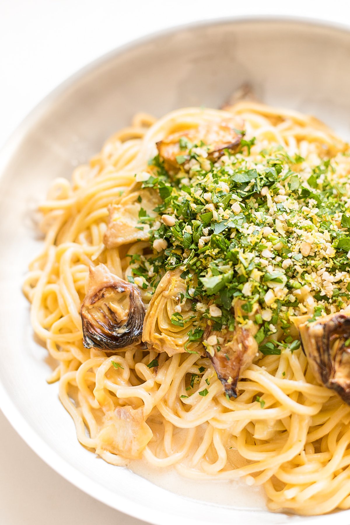 A pan full of lemon spaghetti with fried artichokes.