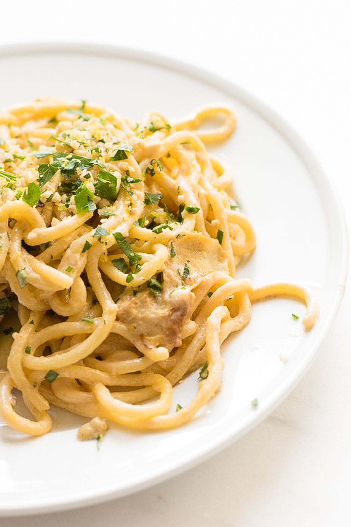 A white plate with a serving of lemon spaghetti.