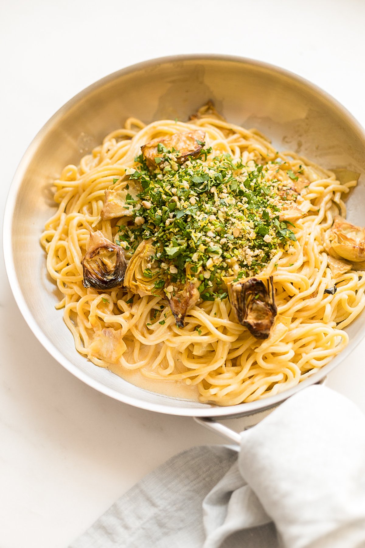 A pan full of lemon spaghetti with fried artichokes. 