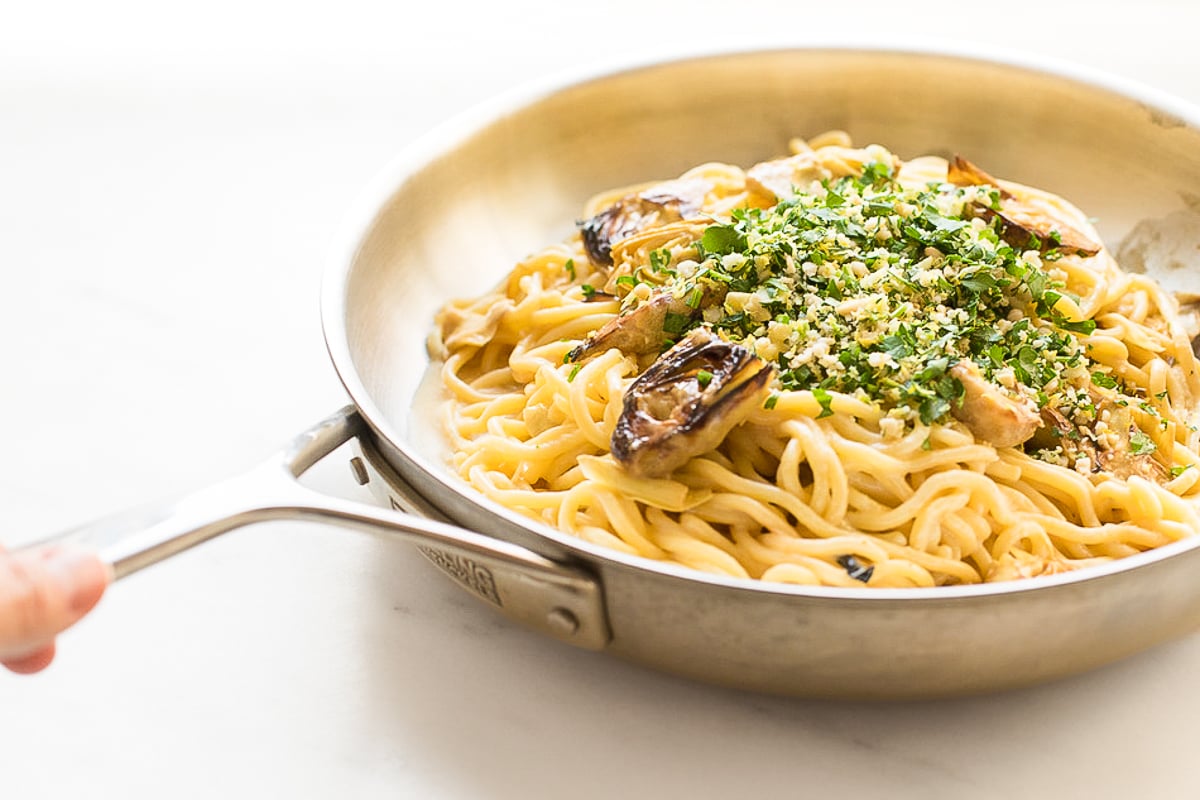 A pan full of lemon spaghetti with fried artichokes.