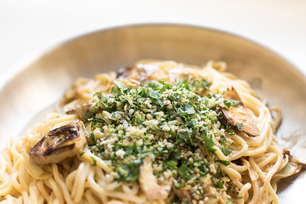 A pan full of lemon spaghetti with fried artichokes.