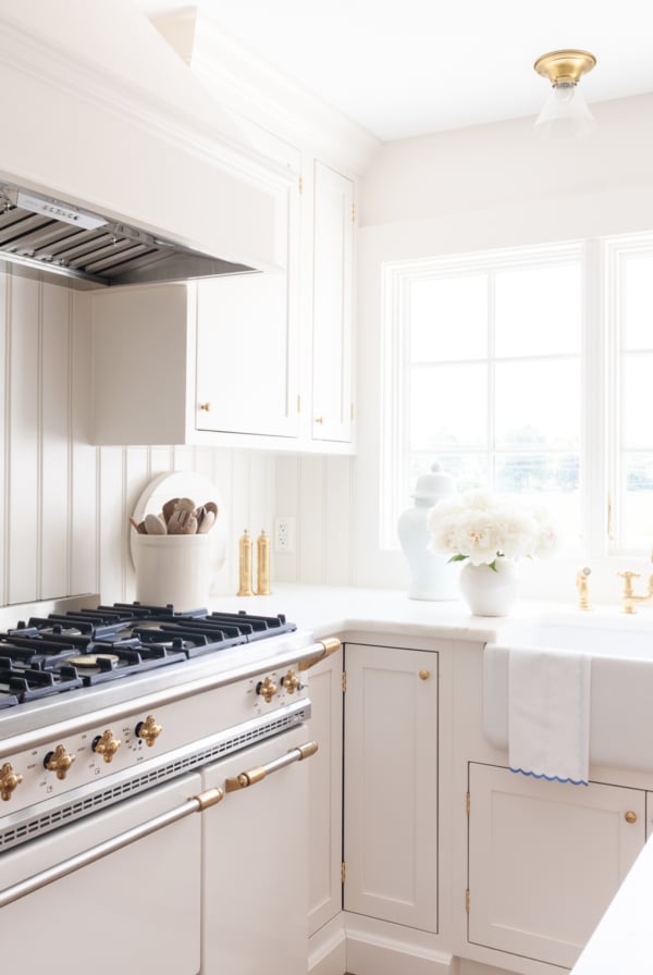 A minimalist kitchen with cream cabinets, marble countertops and a French range.