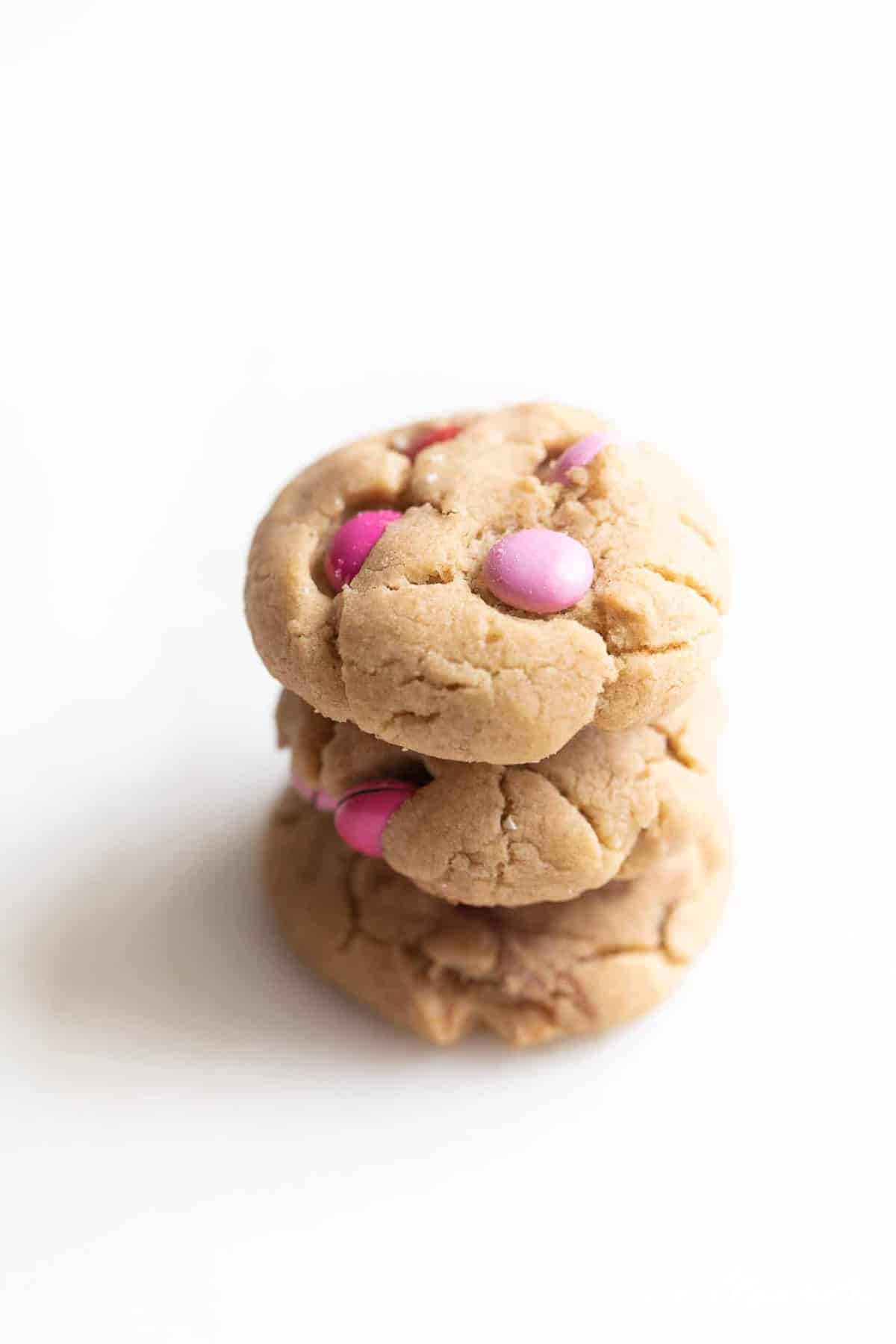 White surface, stack of three m&m cookies.