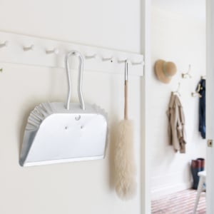 A white mudroom with brick floors and simple mudroom storage bench and hooks.