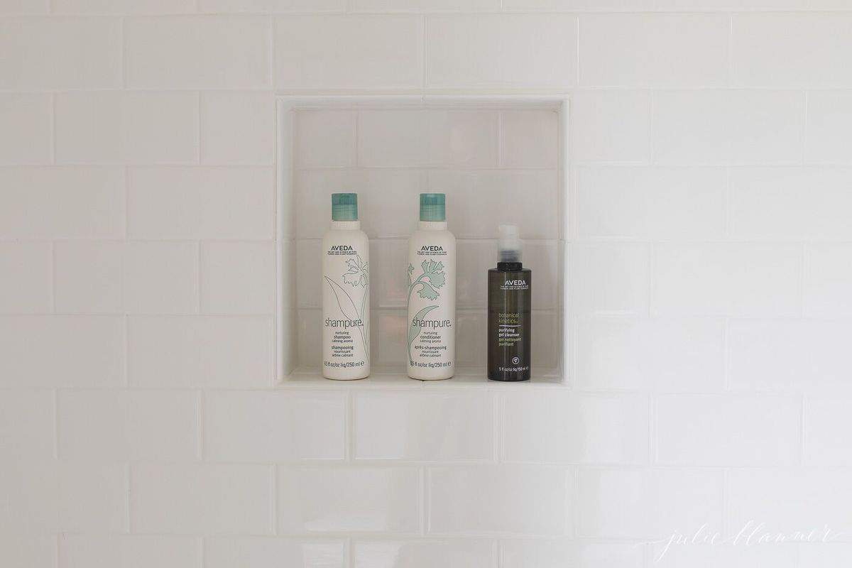 Clean white subway tile in a shower, shampoo bottles in a tile niche.