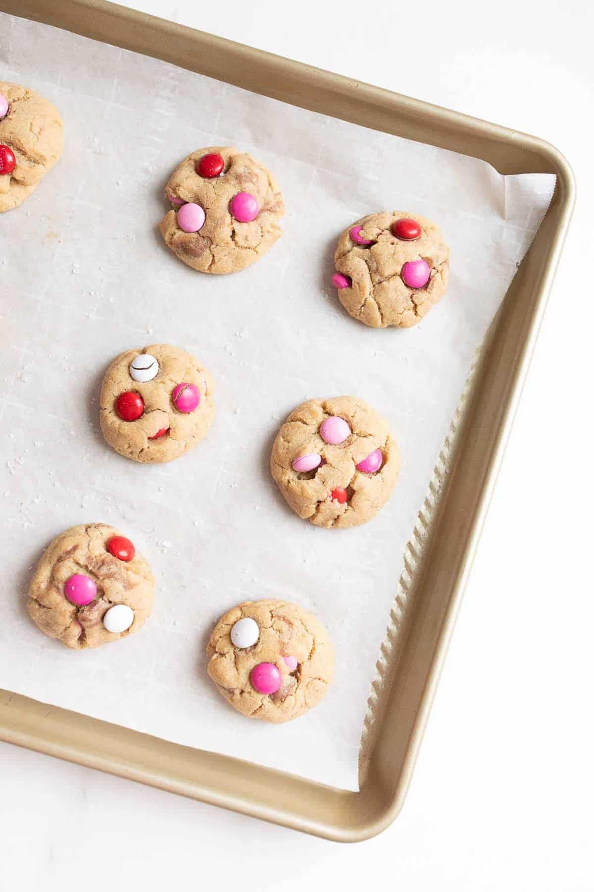 Gold baking sheet filled with Valentine's m and m cookies.