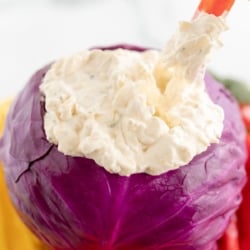 Veggie dip inside a bowl made of purple cabbage