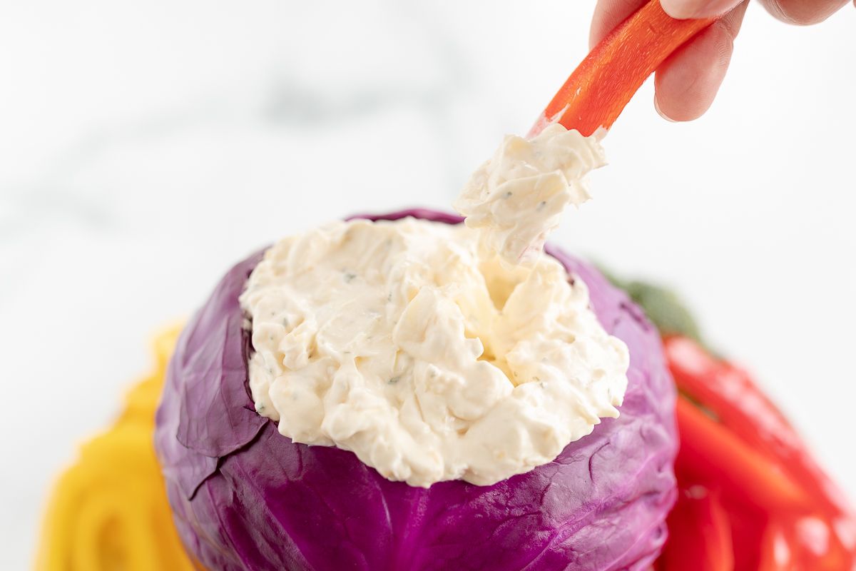 Veggie dip inside a bowl made of purple cabbage