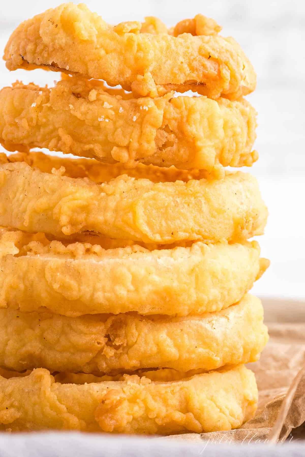 Stack of homemade onion rings on a piece of butcher paper.