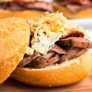 A delicious steak sandwich with tender meat and melty cheese presented on a rustic wooden board.