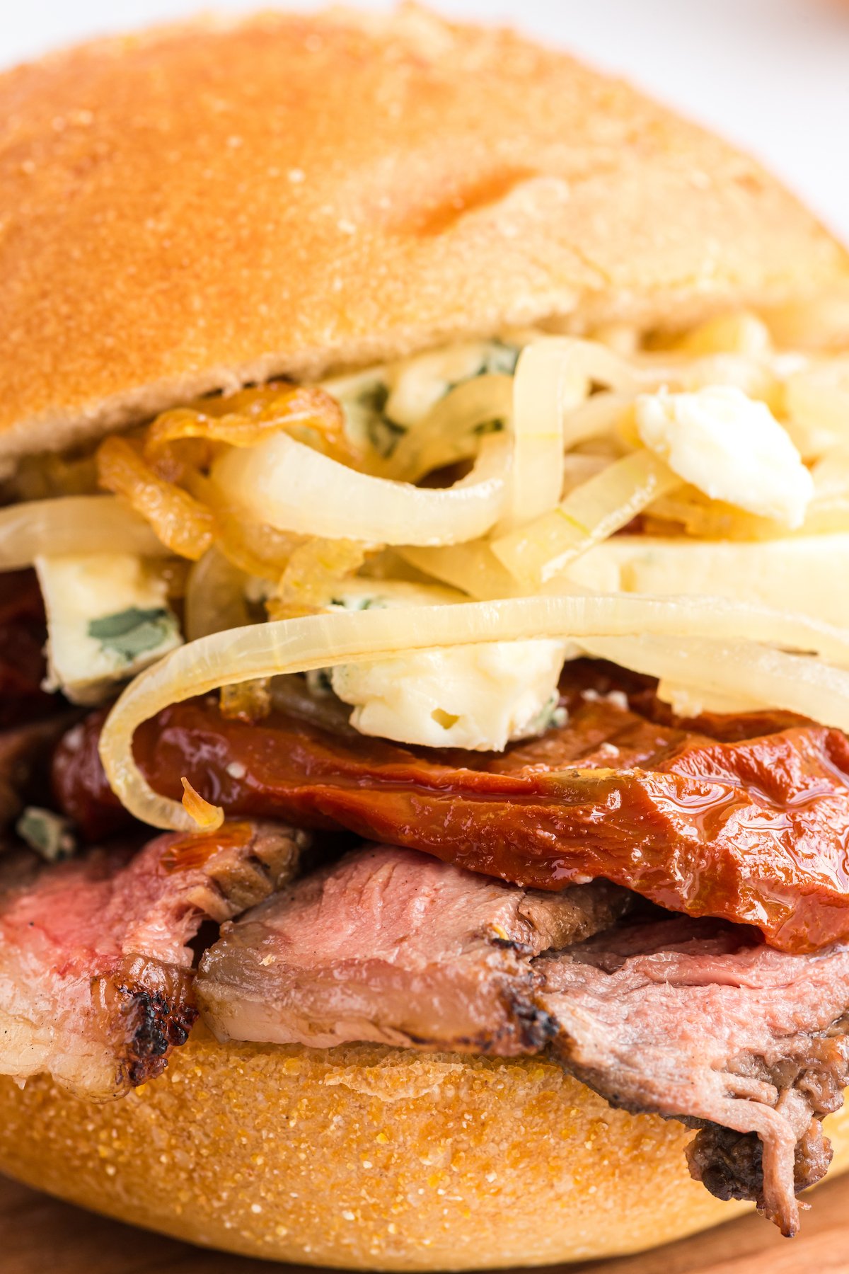A steak sandwich with meat and onions on a wooden board.