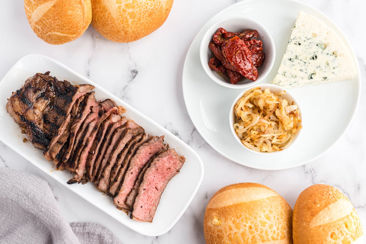 Ingredients for a steak sandwich recipe laid out on a white countertop.