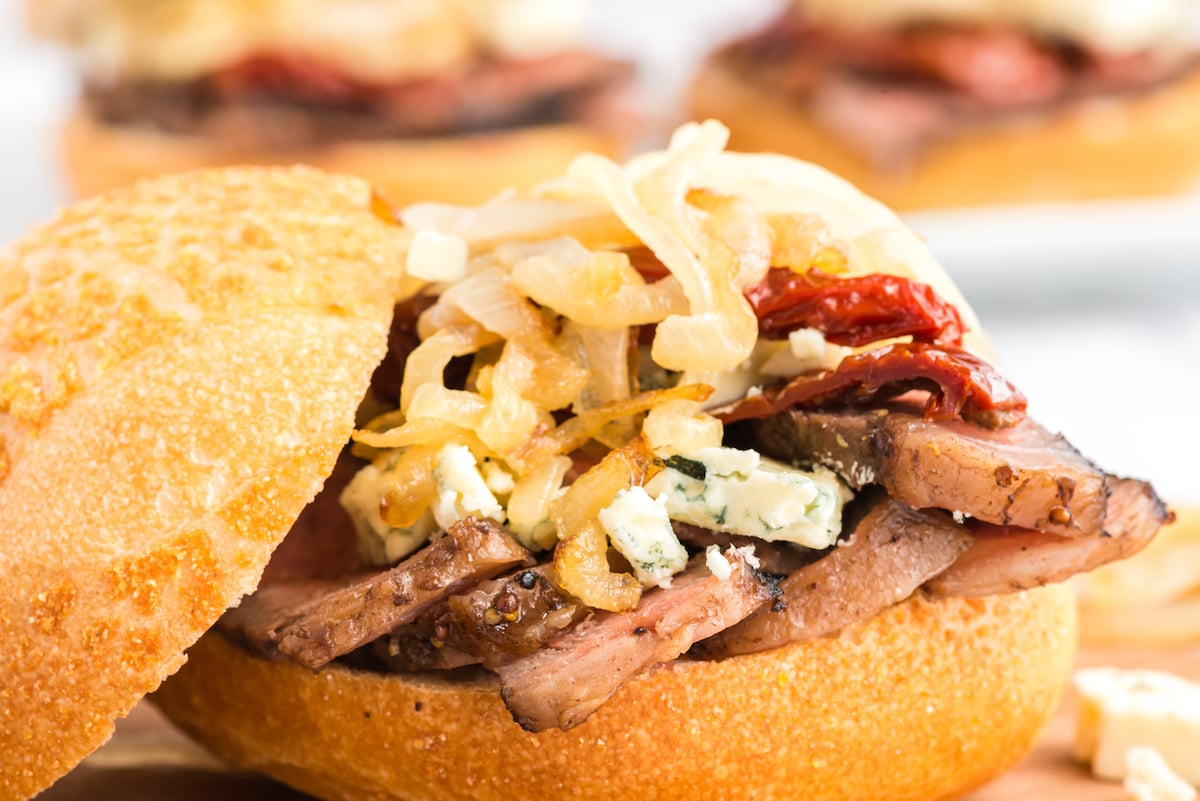 A mouthwatering beef burger topped with tangy blue cheese and caramelized onions, presented on a rustic wooden board.