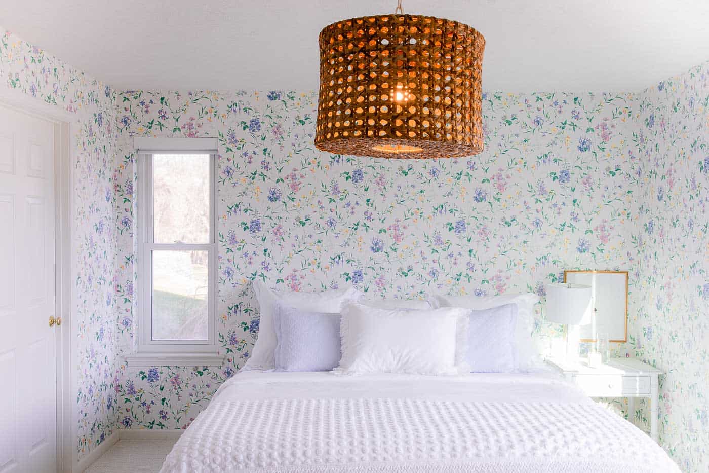 A white bedroom with wooden accents and a statement floral wallpaper. 