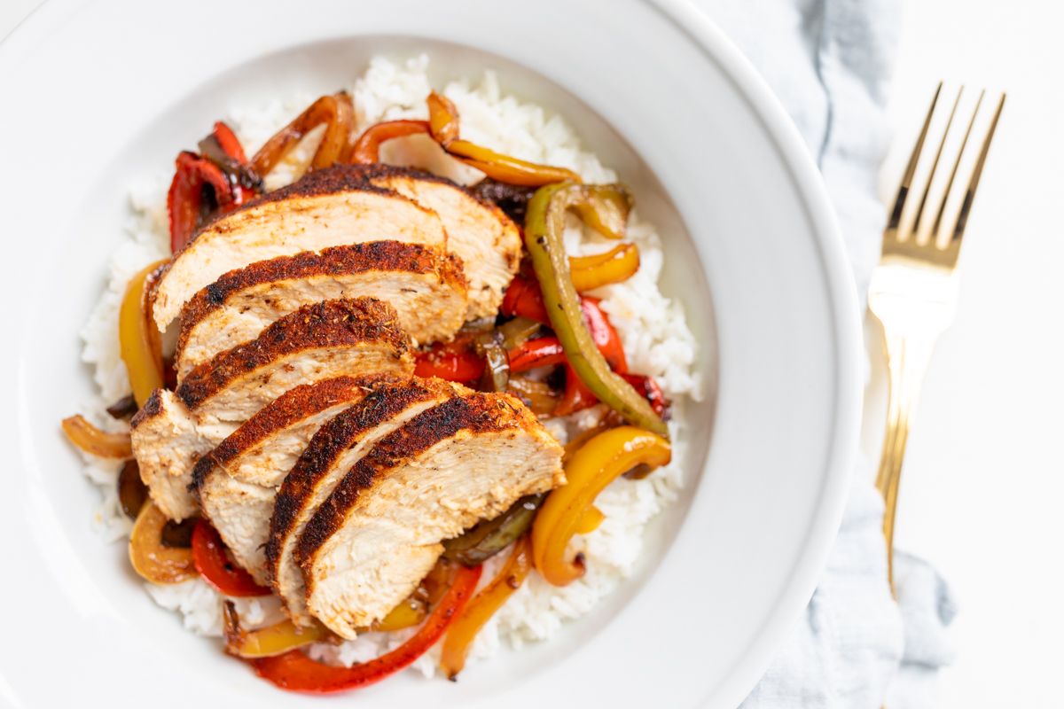 A chicken fajita bowl served over white rice and sauteed peppers.