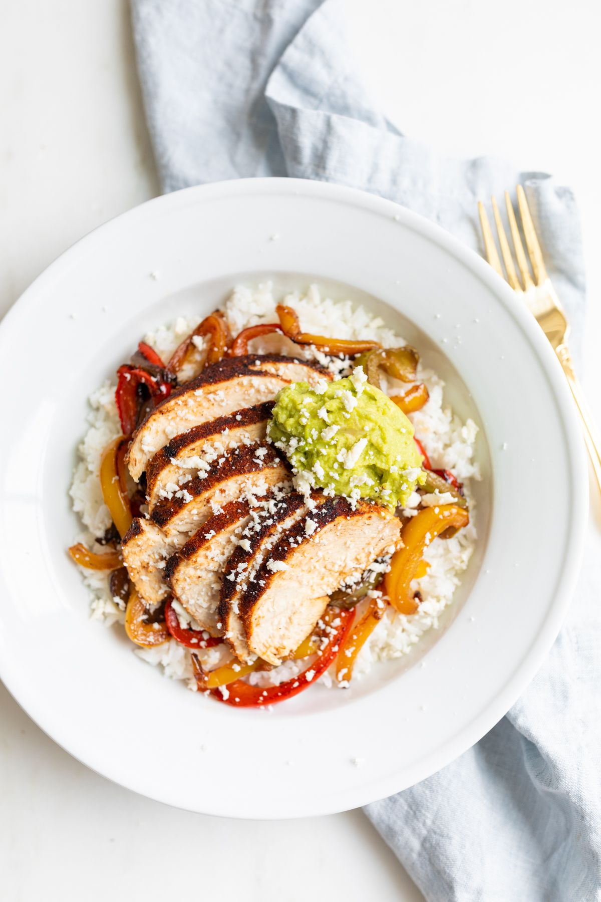 A chicken fajita bowl topped with guacamole.