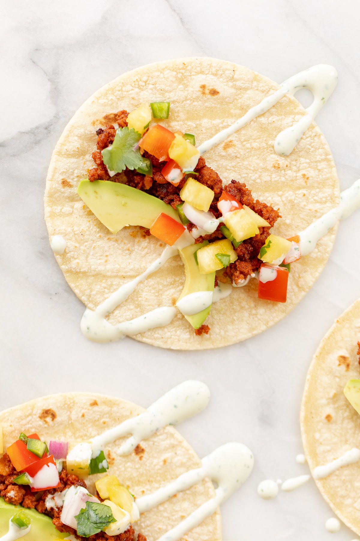 Chorizo tacos topped with avocado, pineapple and lime crema.