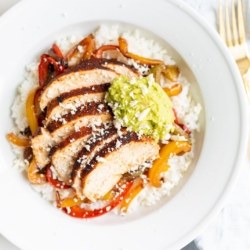 A chicken fajita bowl topped with guacamole.