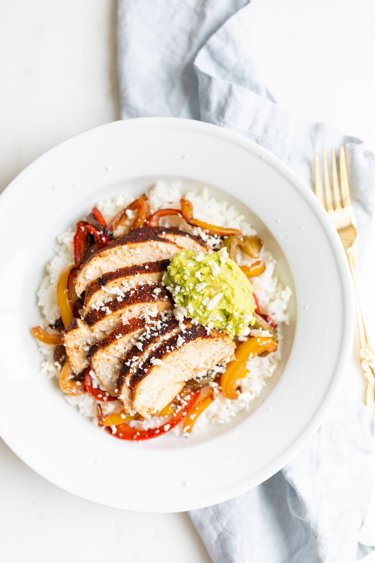 A chicken fajita bowl topped with guacamole. 