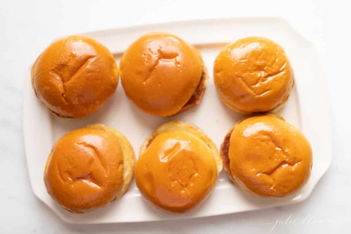 White plate with six burger buns waiting for gourmet burgers.