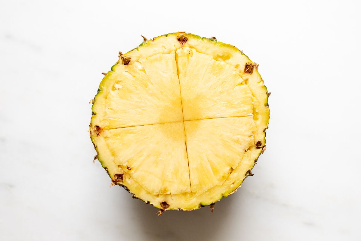 A pineapple, sliced in half and scored across the middle.