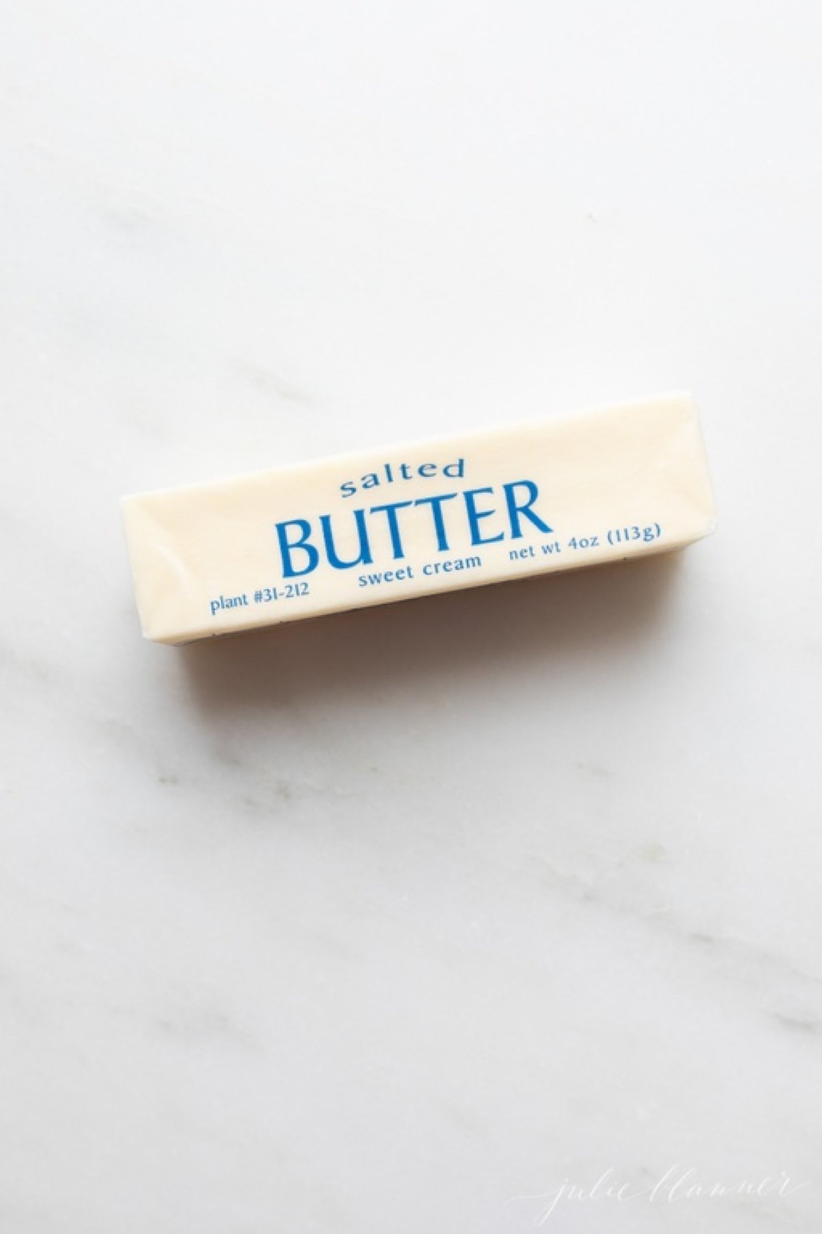 A single stick of salted butter on a marble countertop.