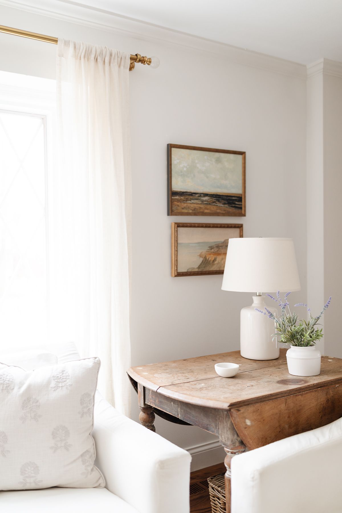 A white living room with white sofas and a wood end table