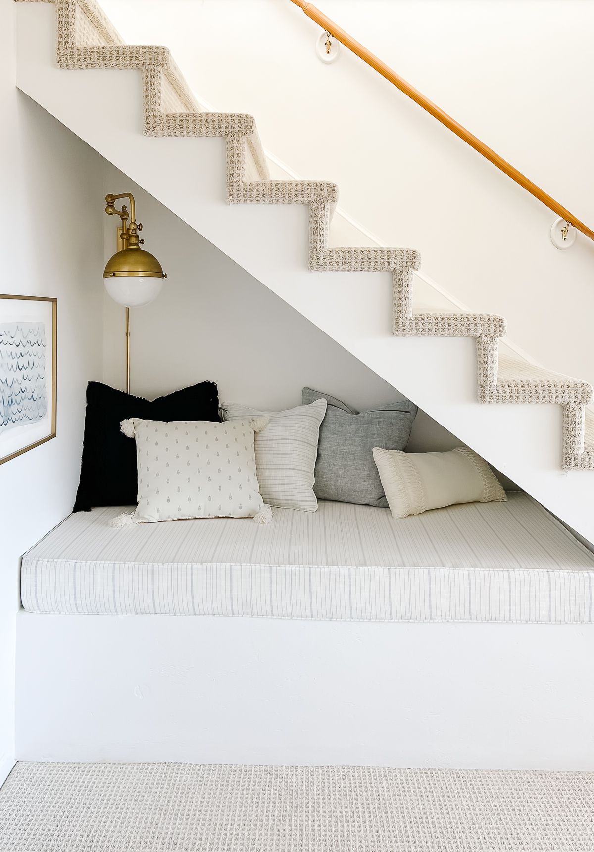 A nook under an open stair case decorated with blue and white pillow covers